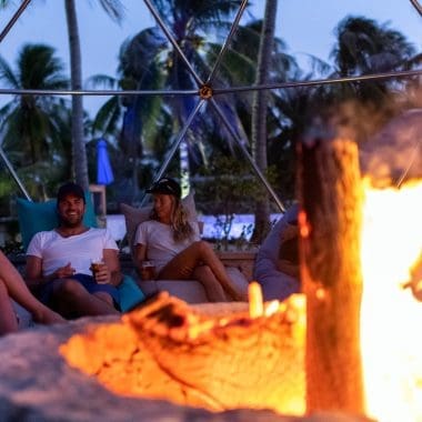 Image of people relaxing by a fire pit at dusk for a blog post on fire pit safety.
