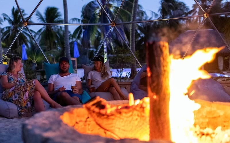 Image of people relaxing by a fire pit at dusk for a blog post on fire pit safety.