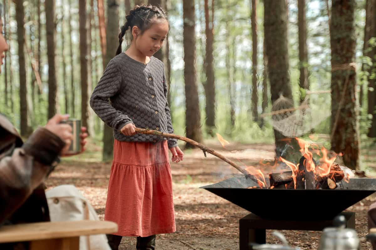 Enjoying outdoor cooking at a backyard campfire with kids, perfect for family camping, outdoor grilling, and backyard fire pits. Cozy and fun fall or summer campfire activity in the woods.