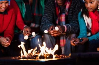 Image of a family roasting marshmallows over a gas fire pit.