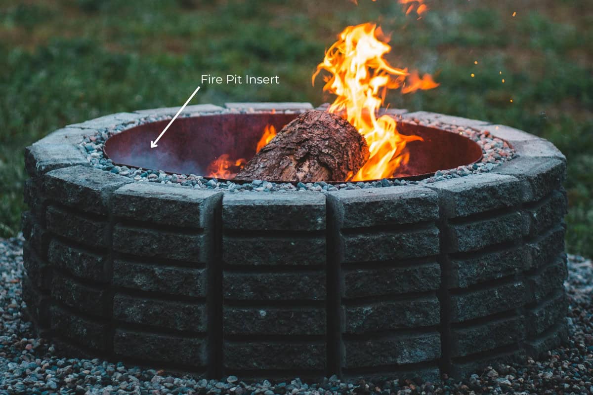 fire-pit-insert-buyers-guide-main Image of a brick fire pit round with a steel fire pit insert