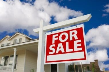 Image of a for sale sign in front of a house for a blog post covering fire pit home value ROI.