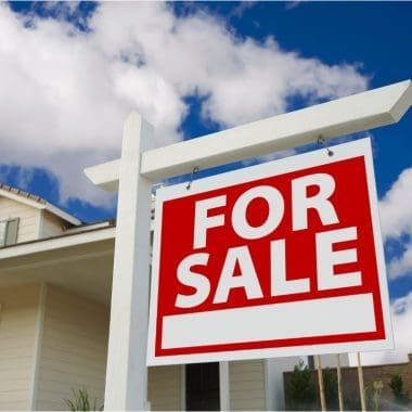 Image of a for sale sign in front of a house for a blog post covering fire pit home value ROI.