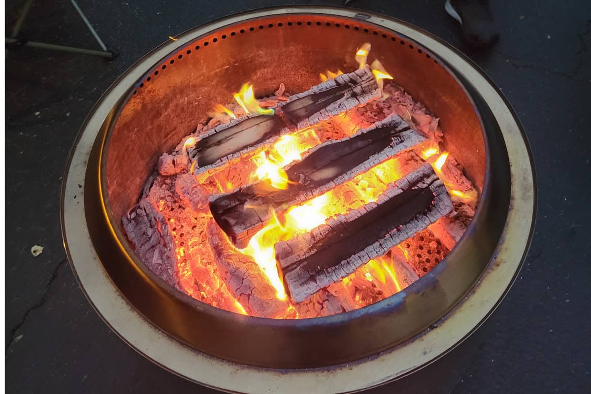 Image of a firewood log-cabin stack burning below the Solo Stove's outlet holes.