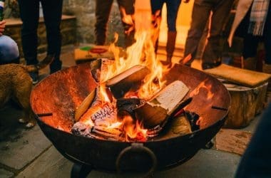 Image of a large round fire pit with people around it for a blog post covering the benefits of a fire pit.