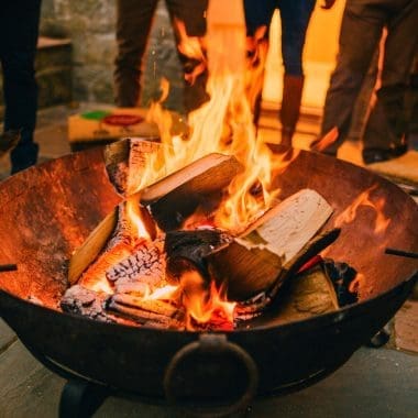 Image of a large round fire pit with people around it for a blog post covering the benefits of a fire pit.
