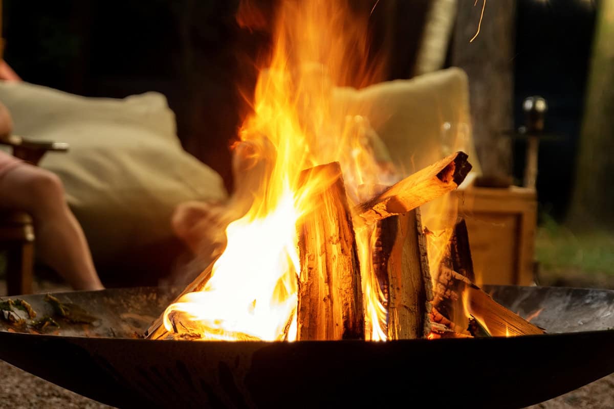 Image of seasoned firewood burning in a fire pit at night.