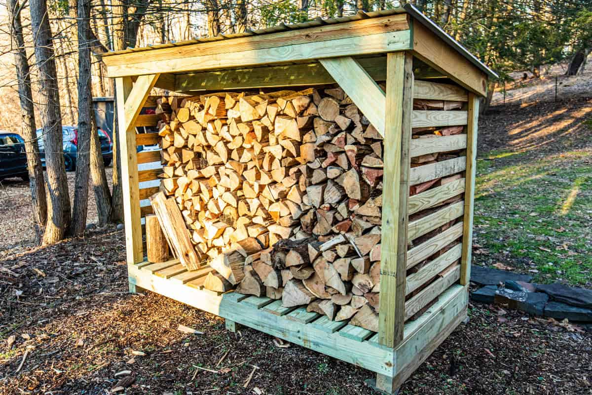 Image of a covered firewood rack keeping seasoning splits off the damp ground.