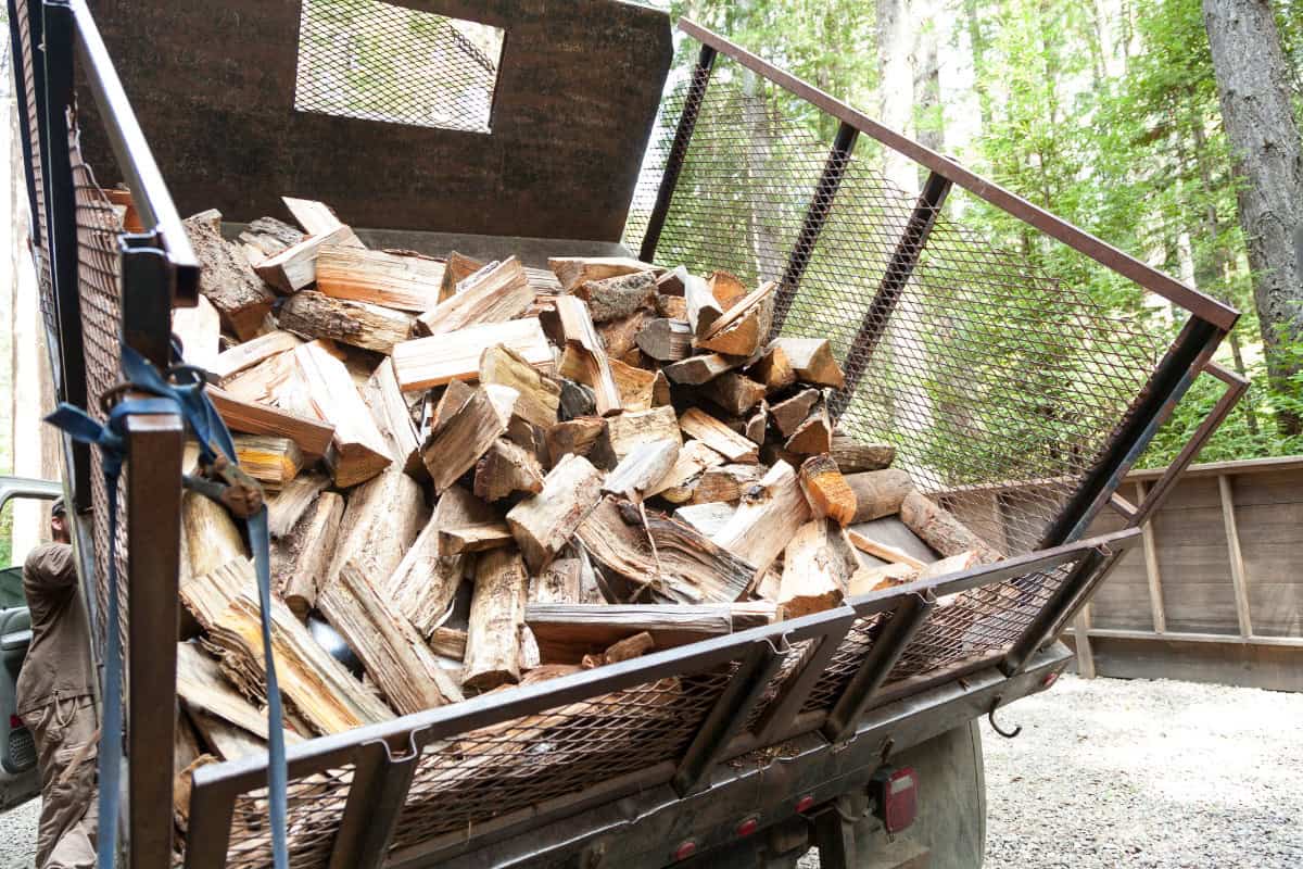 Image of a truck dumping firewood in a driveway.