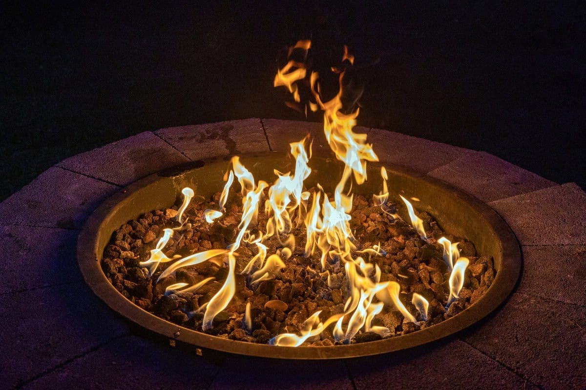 Image of a circular gas fire pit at night.
