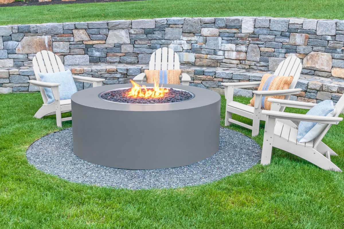 Image of a fixed gas fire pit surrounded by Adirondack chairs.