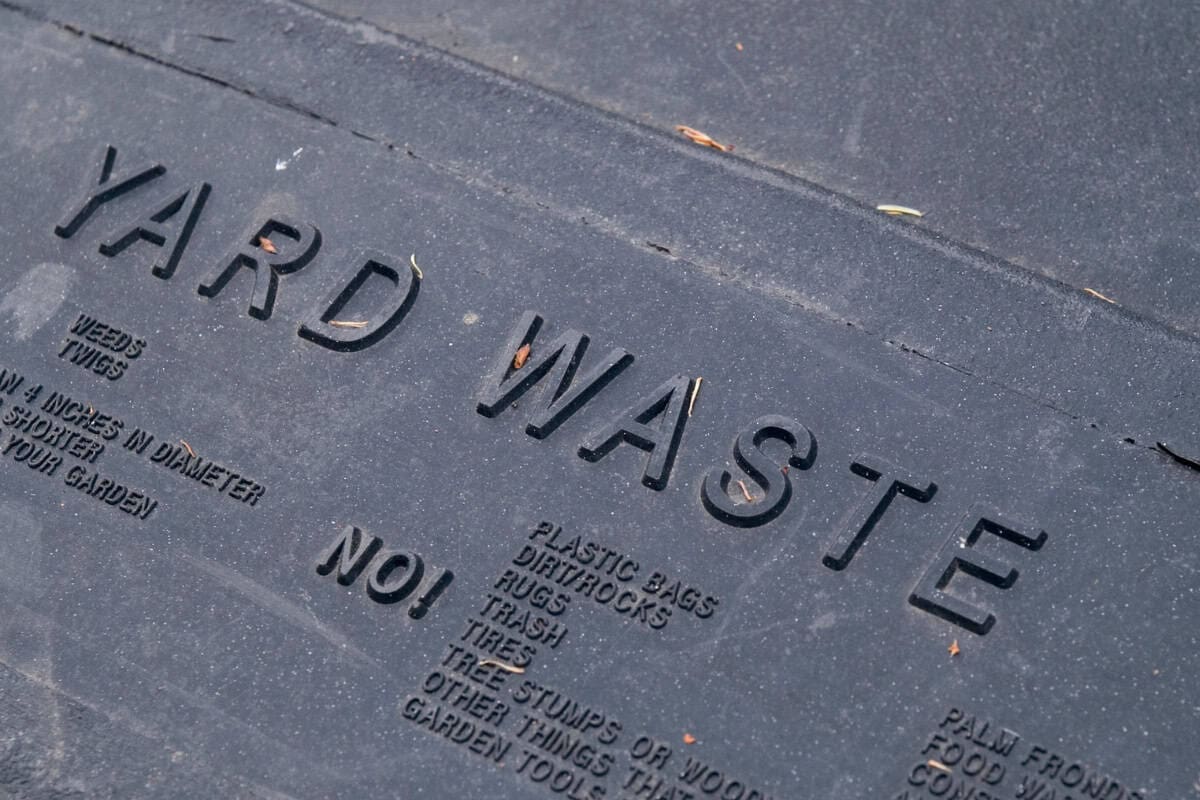 is-a-fire-pit-open-burning-faqs Image of the words "yard waste" on the lid of a waste receptical for a blog post answering the question "is a fire pit open burning?"