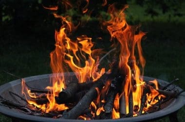 Image of a lit wood-burning fire pit early in the evening for a blog post answering the question "is a fire pit open burning?"