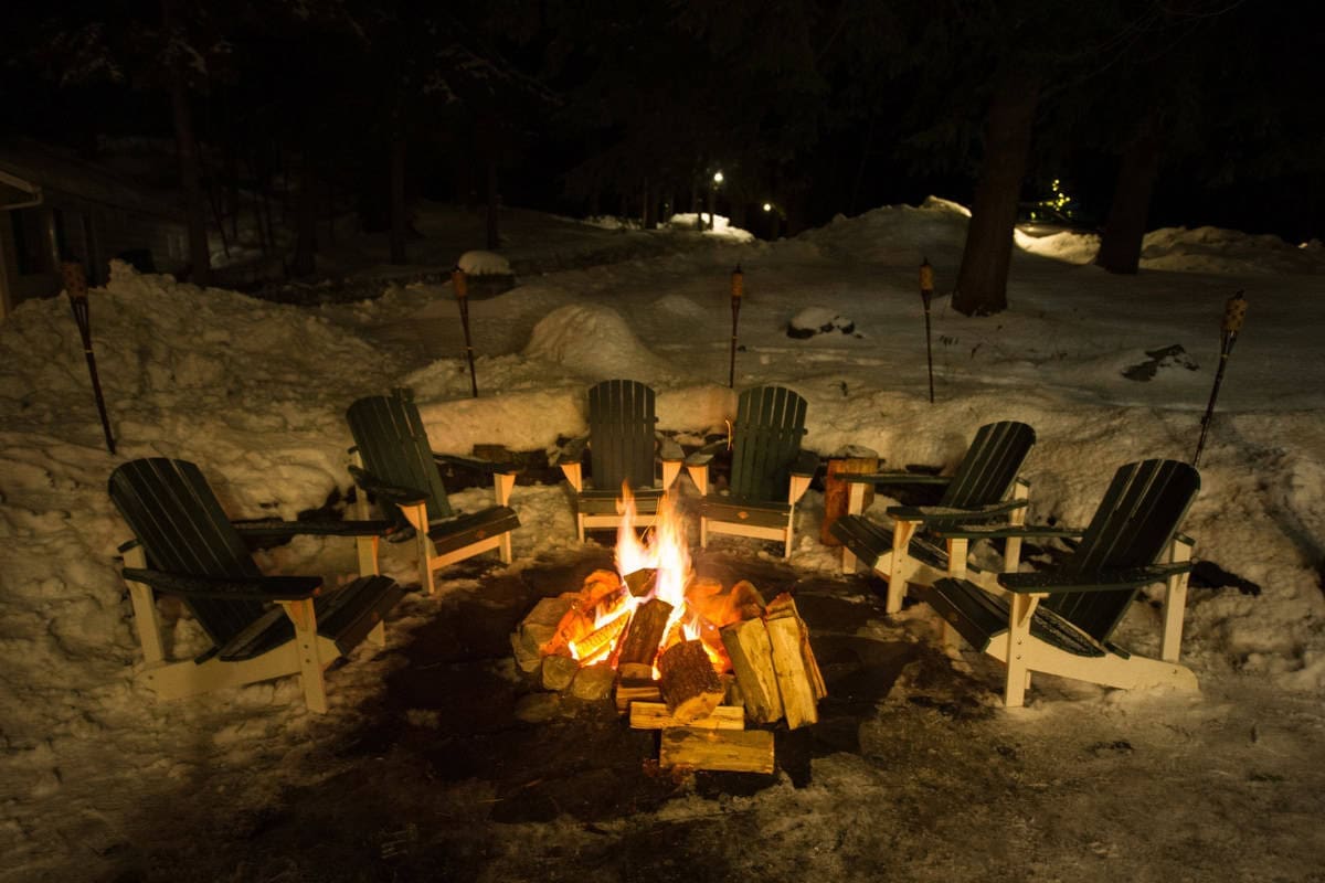 What is Open Burning? Image of a burning fire pit surrounded by Adirondack chairs after a heavy snowfall.
