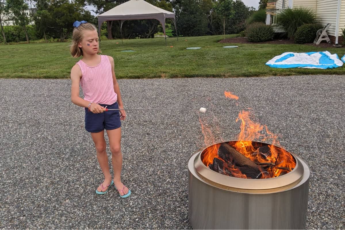 Kids roasting marshmallows over a backyard fire pit for outdoor fun. Perfect for family gatherings and outdoor entertainment, creating warm memories around the fire.