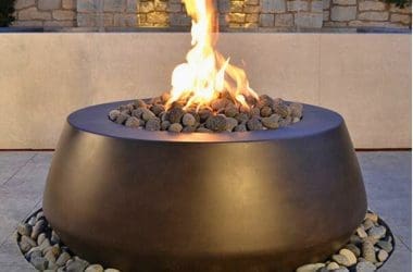 Image of a round gas fire pit on a patio for a blog post covering fire pit media.