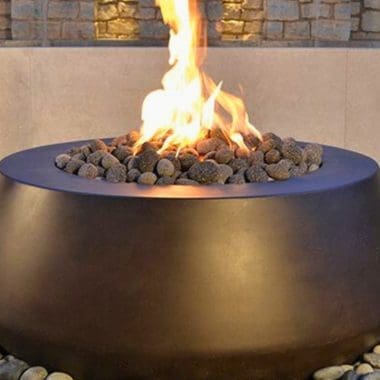 Image of a round gas fire pit on a patio for a blog post covering fire pit media.