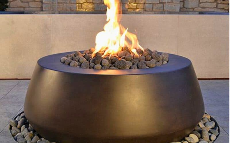 Image of a round gas fire pit on a patio for a blog post covering fire pit media.