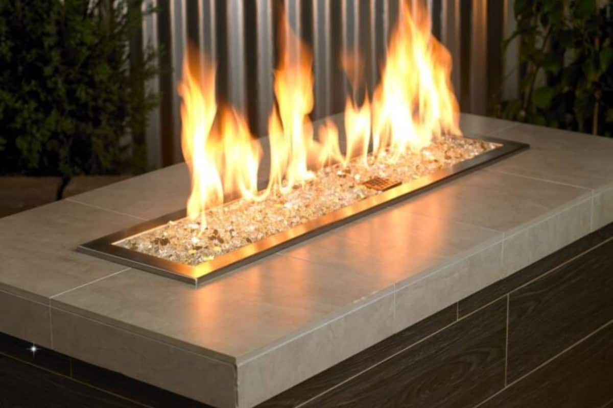Image of a rectangular gas fire pit with clear fire glass for a blog post about fire pit media.