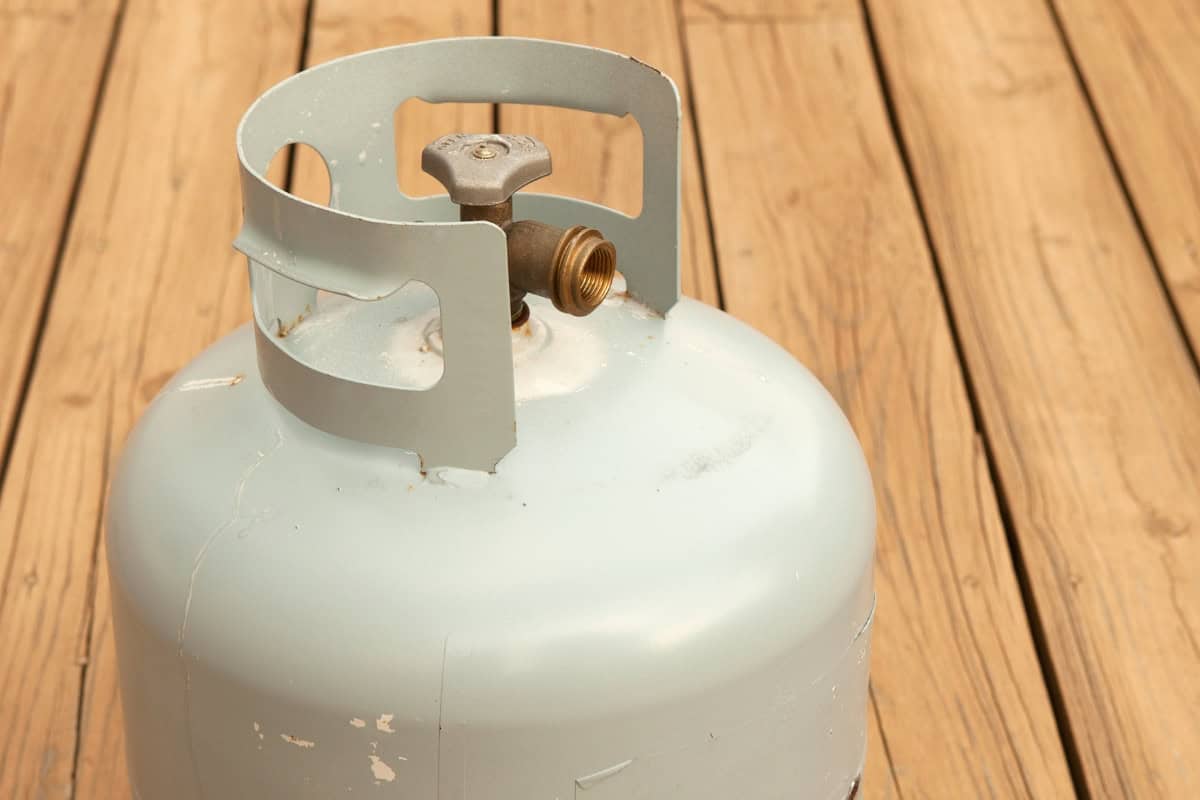 Image of a 20 lb. propane tank on a wood deck for a page featuring a fire pit propane usage estimator.
