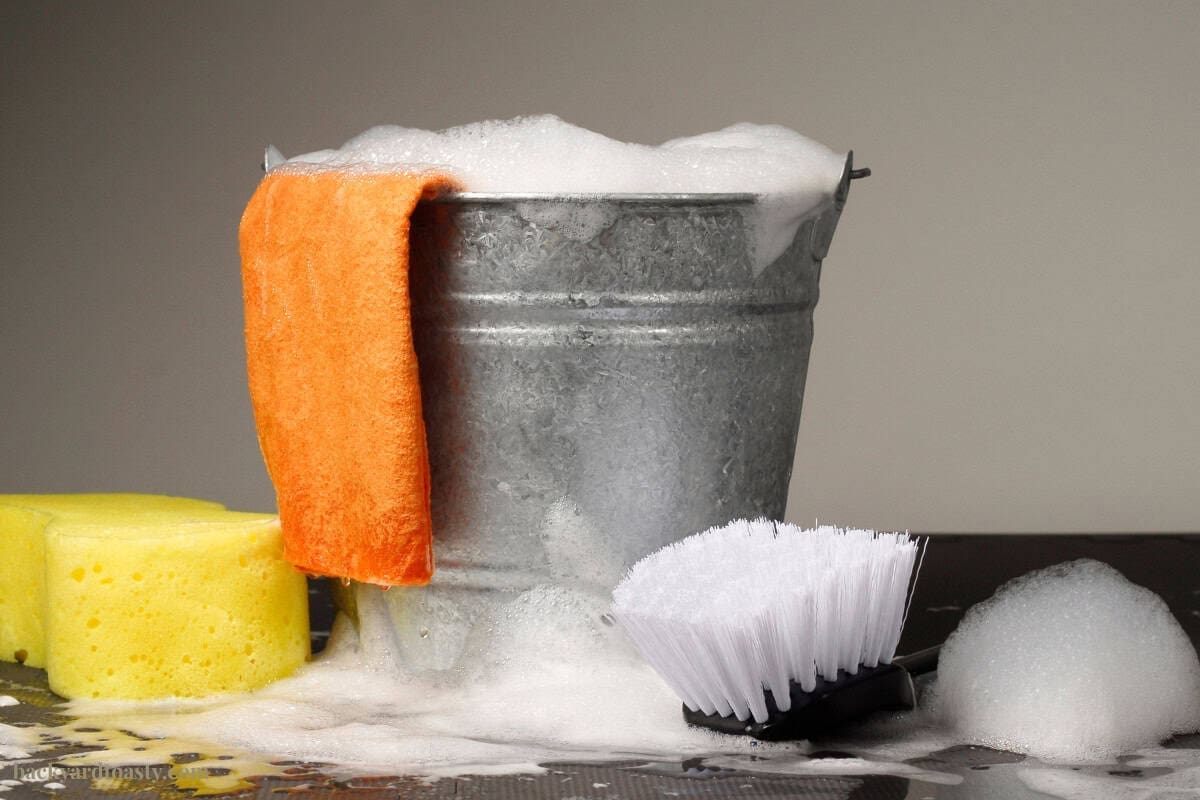 Image of a bucket of soapy water, rags and brush.