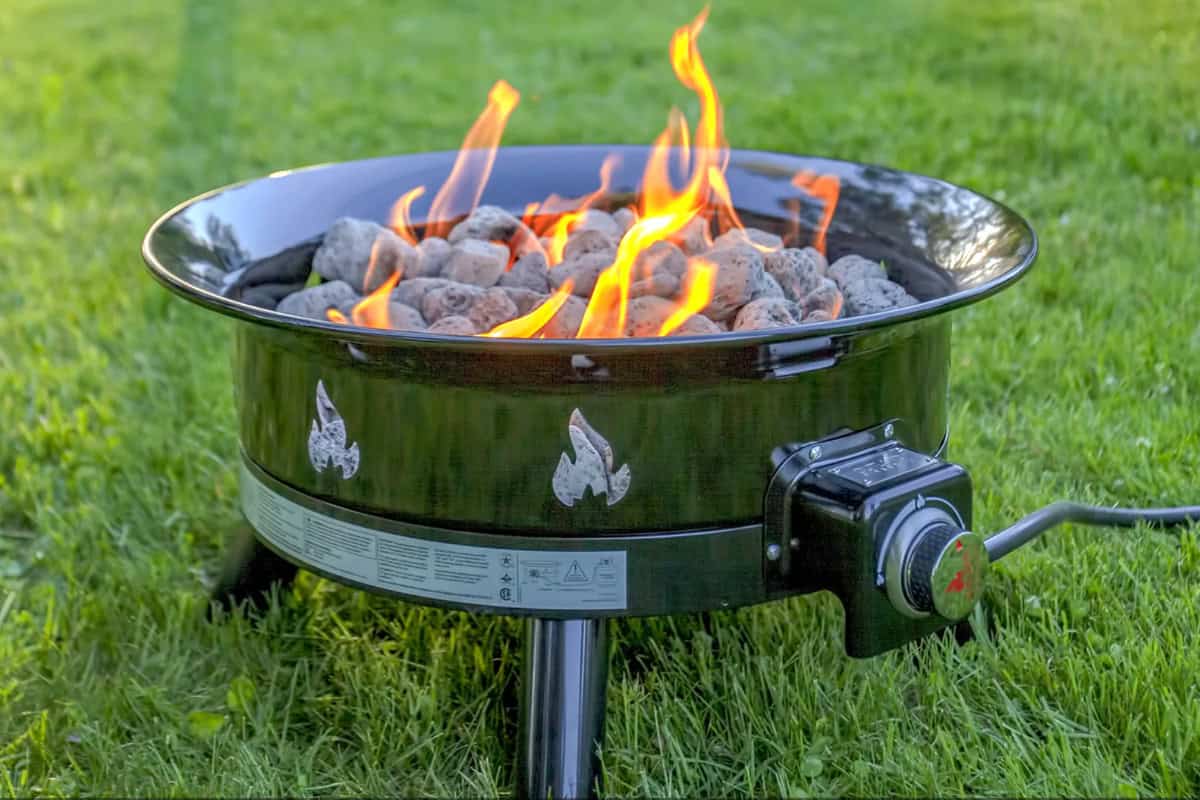 outland-living-mega-fire-pit-review-benefits Image of a portable gas fire pit on grass.
