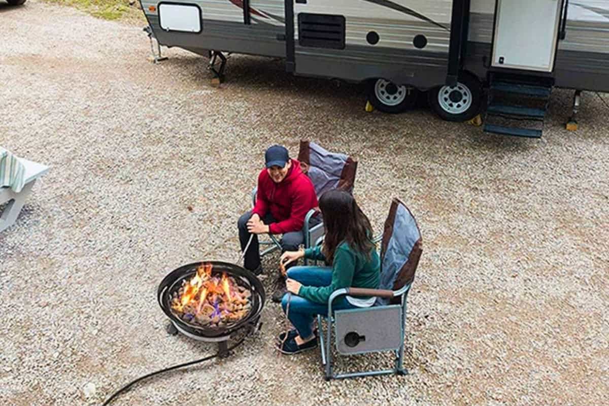 outland-living-mega-fire-pit-review-efficiency Image of a man and a woman warming by a fire pit at a campsite.