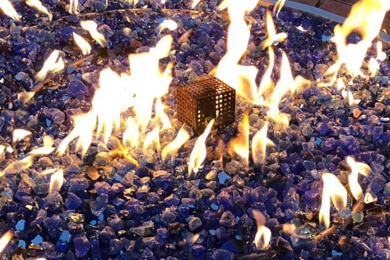 Image of a burning natural gas fire pit at night for a blog post about various fire pit fuels.