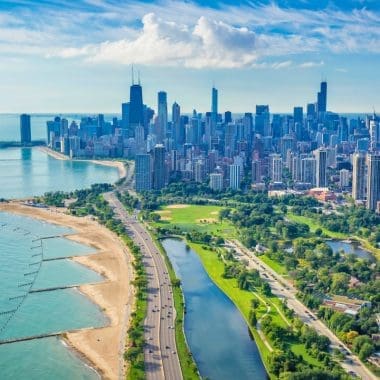 Vibrant aerial view of Chicago skyline with Lake Michigan, city park, and lush greenery, showcasing urban landscapes and outdoor recreation opportunities in a bustling metropolitan area.
