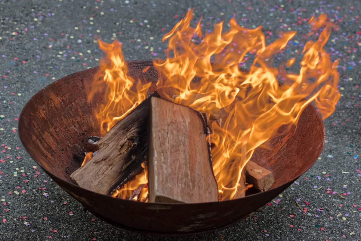Image of a burning fire pit bowl on asphalt for a guide covering city fire pit rules.
