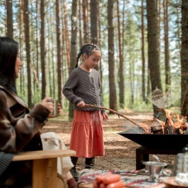Cozy outdoor camping scene with children roasting food over an open fire in a wooded forest setting, featuring a backyard toast backyard toastymark every element for outdoor dining and camping enjoyment.