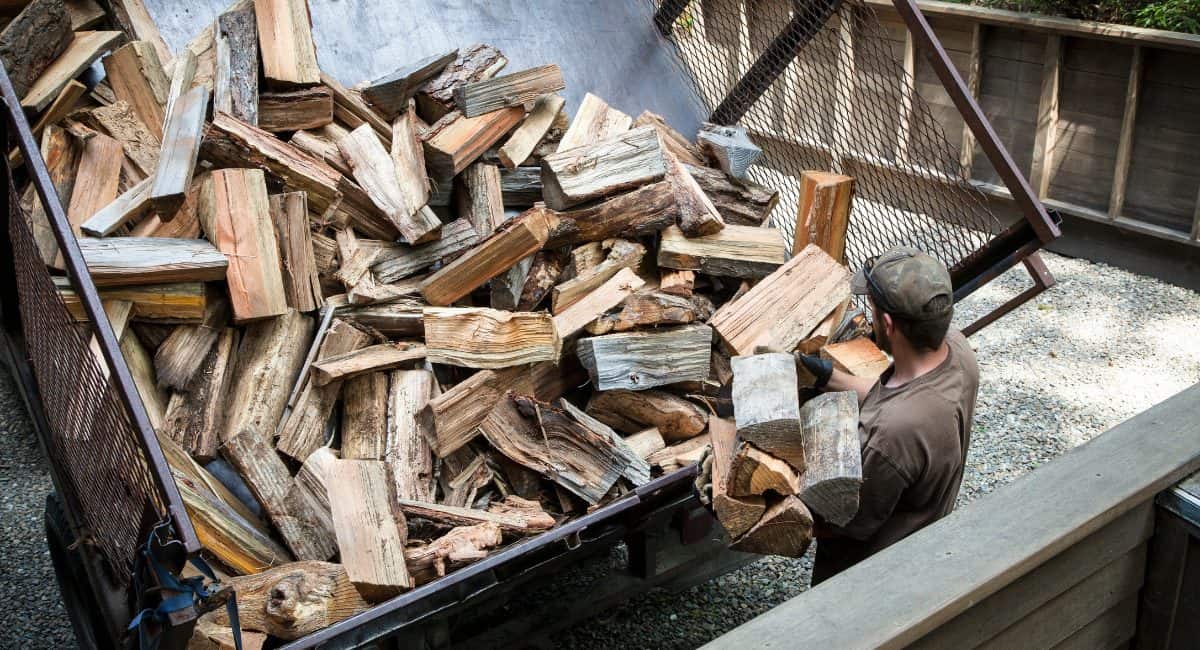 Image of a man delivering firewood to a home for the site's firewood vendor directory.