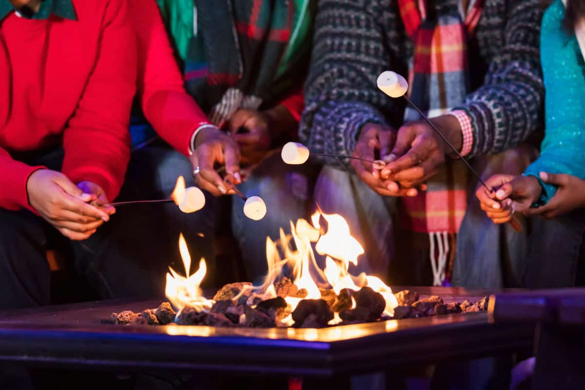 Image of a family roasting marshmallows over a gas fire pit.