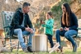 Image of a family roasting sausages over a smokeless fire pit for an article covering the best fire pit for suburban backyard use.