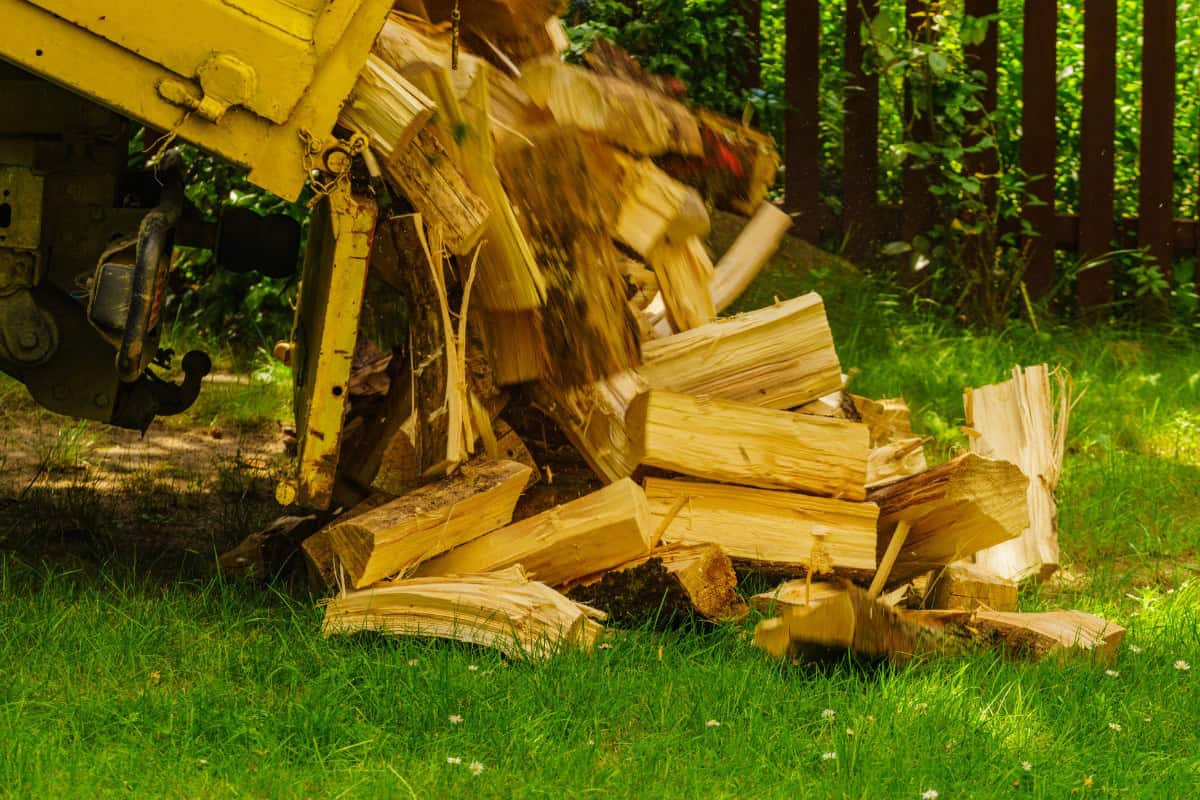 canadian-firewood-prices-market-outlook Image of a truck dumping a load of split firewood on a home's lawn.