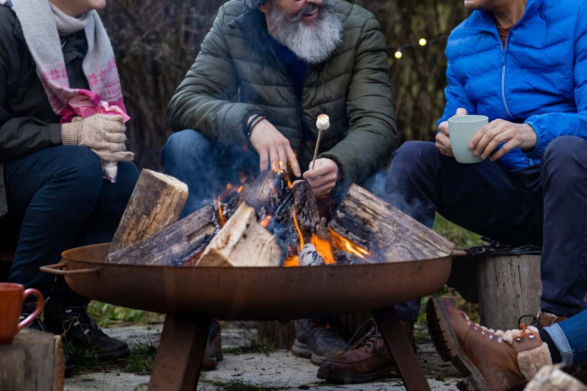 canadian-firewood-prices-wrap-up Image of four people sitting around a burning fire pit on a cool fall day for a post on Canadian firewood prices.