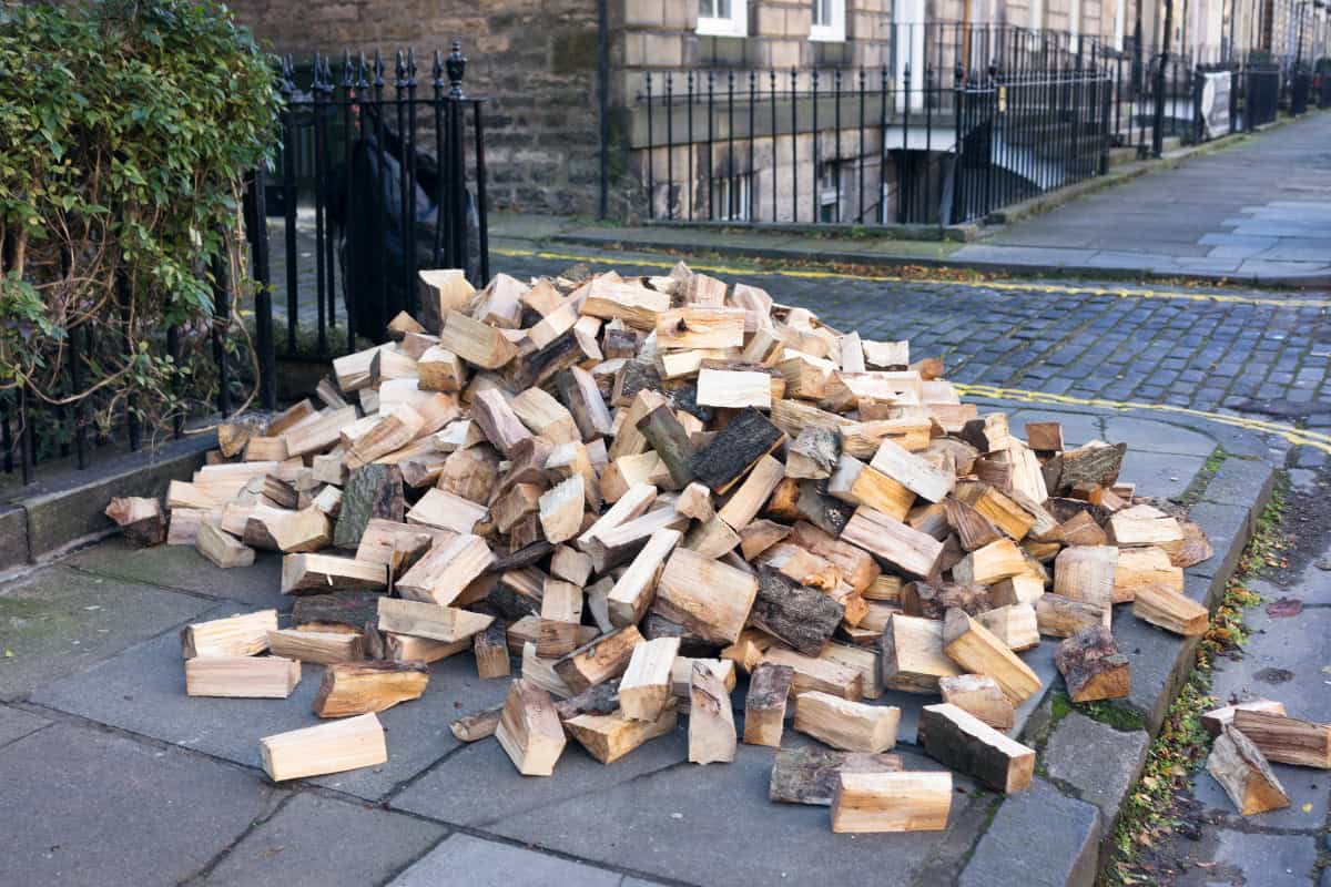 Image of a pile of firewood dumbed on a sidewalk in front of a home for a blog post on UK firewood prices.
