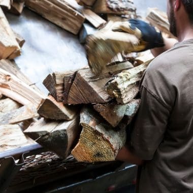 Image of a man delivering firewood to a home for a post on UK firewood prices.