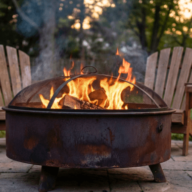 Image of a wood-burning fire pit in a backyard surrounded by chairs for a post covering fire pit safety features.